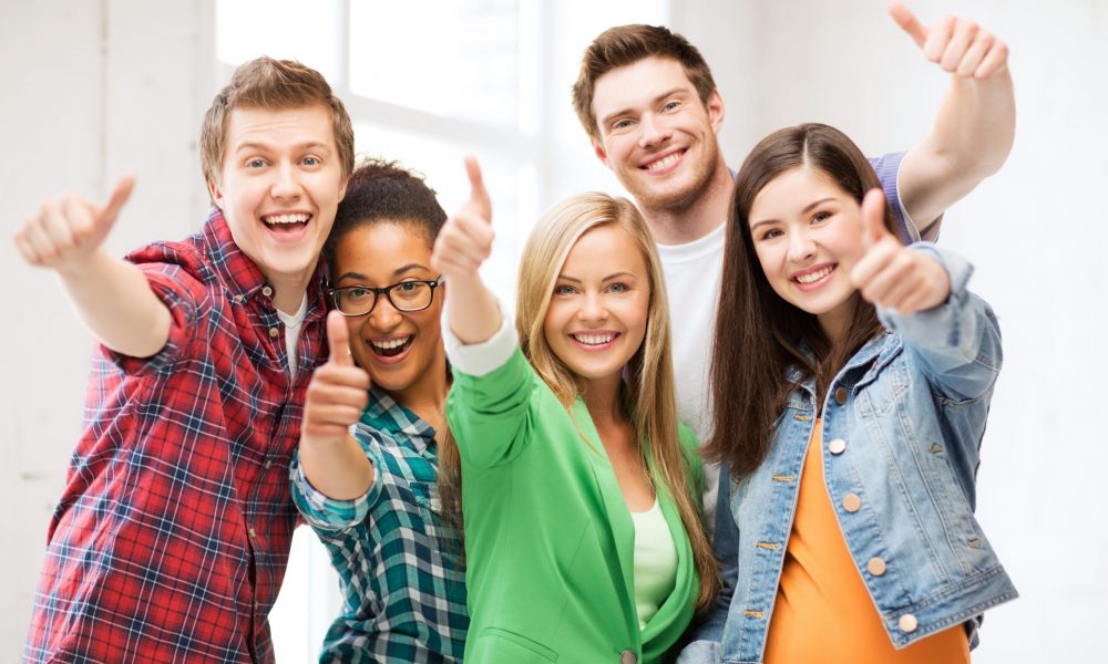 education concept - happy team of students showing thumbs up at school