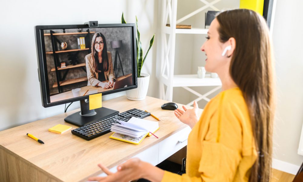 Video call, virtual meeting. Two young female co-workers is talking online via video connection