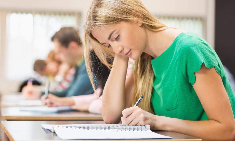 Side view of a group of young students writing notes in the classroom